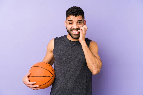 Young latin man playing basket isolated biting fingernails, nervous and very anxious.