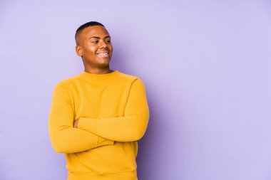 Young latin man isolated on purple background smiling confident with crossed arms.