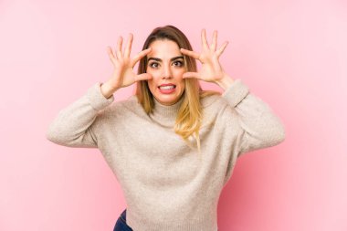 Middle age woman over isolated background keeping eyes opened to find a success opportunity.
