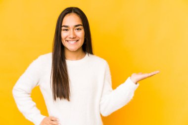 Sarı arka planda izole edilmiş genç bir kadın bir avuç içinde fotokopi alanı ve belinde bir el daha olduğunu gösteriyor..