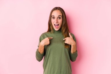 Kafkasyalı bir kadın yalnız poz veriyor. Parmakla işaret ediyor, gülümsüyor..