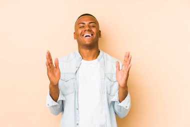 Young latin man isolated on beige background joyful laughing a lot. Happiness concept.