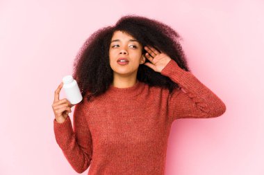 Vitamin tutan genç bir afro kadın. Bir dedikoduyu dinlemek için vitaminli genç bir afro kadın..