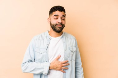 Genç melez Arap adam karnına dokunuyor, nazikçe gülümsüyor, yemek yiyor ve tatmin oluyor..