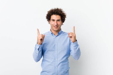 Zarif bir gömlek giyen genç, kıvırcık, olgun bir adam her iki elini de boş bir alan göstererek gösterir..