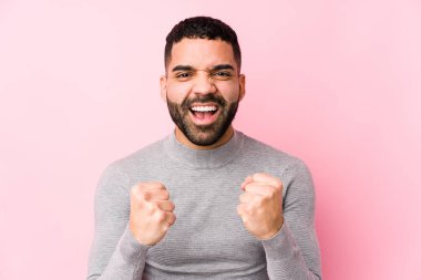 Pembe arka planda genç bir latin adam yalnız, kaygısız ve heyecanlı. Zafer konsepti.
