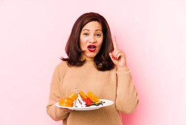 Orta yaşlı, elinde waffle tutan Latin bir kadının harika bir fikri var, yaratıcılık kavramı..