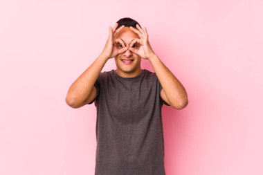 Pembe arka planda poz veren yog latin adam gözlerinde sorun olmadığını gösteriyor.