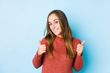 Kafkasyalı genç bir kadın yalnız poz veriyor. Baş parmağını kaldırıyor, gülümsüyor ve kendinden emin..