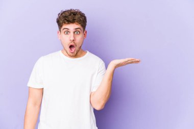 Sarışın, kıvırcık saçlı, beyaz tenli bir adam avucunun içinde fotokopi yeri tutmaktan etkilenmiş..