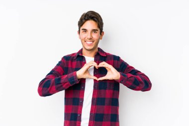Pembe arka planda poz veren beyaz bir genç izole edilmiş gülümseyen ve elleriyle kalp şeklini gösteren bir adam..
