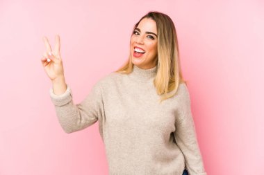 Middle age woman over isolated background joyful and carefree showing a peace symbol with fingers.