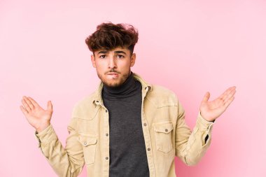 Arka planda poz veren genç Arap bir adam. Kopya alanını tutmak için kafası karışık ve omuz silkiyor..