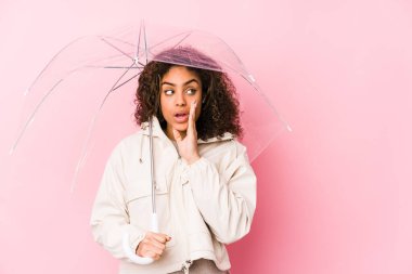 Şemsiye tutan Afrikalı Amerikalı genç bir kadın gizli bir sıcak fren haberi veriyor ve yan bakıyor.