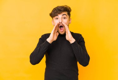 Sarı arka planda izole edilmiş genç bir Arap adam heyecanlı bir şekilde bağırıyor..