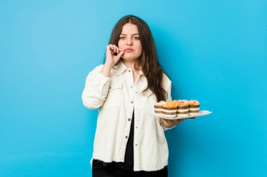 Genç, kıvrımlı bir kadın, parmakları dudaklarında keklerle bir sır saklıyor..