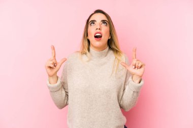 Middle age woman over isolated background pointing upside with opened mouth.