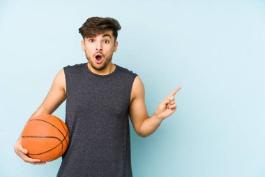 Yan tarafı işaret eden, basket oynayan genç bir Arap.