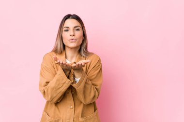 Beyaz tenli genç bir kadın, dudaklarını katlayıp, avuç içi tutarak hava öpücüğü yolluyor..