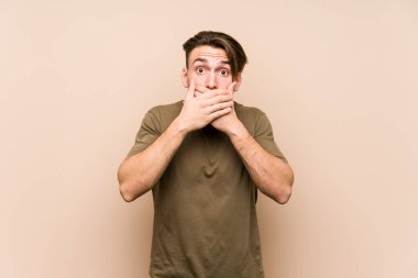Kafkasyalı genç adam yalnız poz veriyor. Elleriyle ağzını kapatıyor..