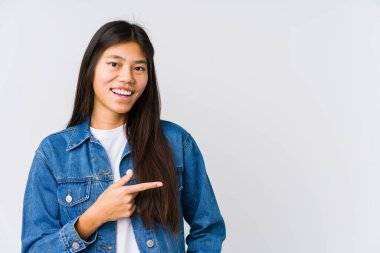 Genç Asyalı kadın gülümsüyor ve boş alanda bir şeyler gösteriyor..
