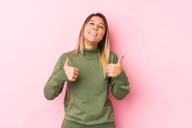 Kafkasyalı genç bir kadın yalnız poz veriyor. Baş parmağını kaldırıyor, gülümsüyor ve kendinden emin..