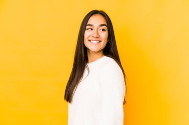 Sarı arka planda soyutlanmış genç bir kadın. Gülümsüyor, neşeli ve keyifli görünüyor..