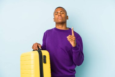 Genç bir gezgin, izole edilmiş bir bavul tutuyor. Seni işaret ediyor. Sanki seni davet ediyormuş gibi..