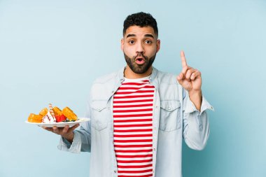 Elinde waffle tutan genç latin adamın harika bir fikri var, yaratıcılık kavramı..