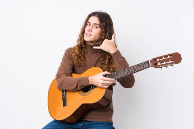 Gitar çalan beyaz bir adam izole edilmiş bir şekilde cep telefonuyla işaret ediyor..