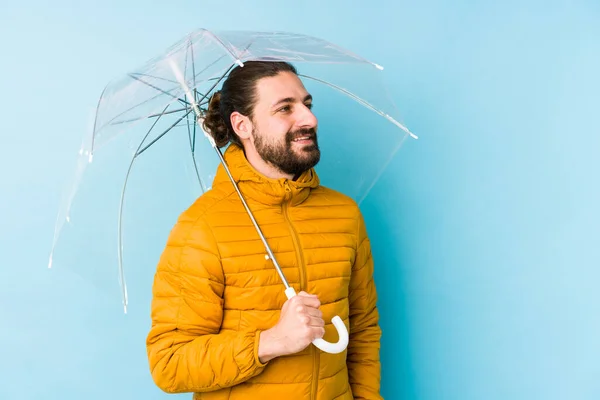 若い男は長い髪を見て傘を保持身に着けている独立した表情脇笑顔 陽気で快適な — ストック写真