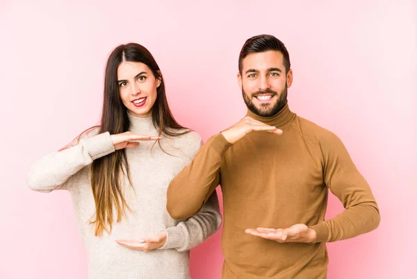 Jovem Casal Caucasiano Isolado Segurando Algo Com Duas Mãos Apresentação — Fotografia de Stock