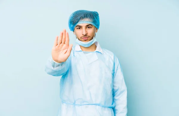 Молодий Арабський Хірург Ізольований Синьому Фоні Стоїть Простягнутою Рукою Показуючи — стокове фото