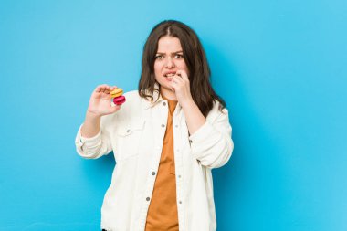 Kurabiye tutan, tırnaklarını yiyen, gergin ve endişeli bir kadın..