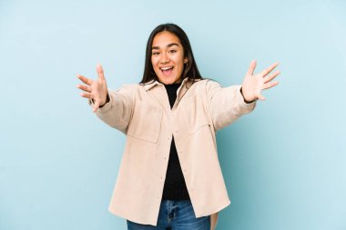 Mavi arka planda izole edilmiş genç bir kadın kameraya sarıldığı için kendinden emin hissediyor..