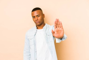 Genç latin adam bej arka planda izole edilmiş, elini uzatmış, dur işareti göstererek seni engelliyor..