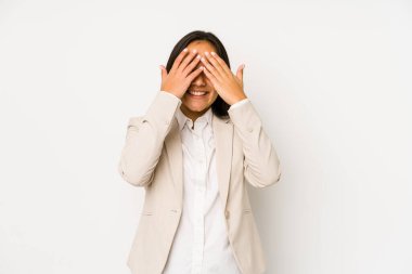 Beyaz bir arka planda izole edilmiş genç bir kadın elleriyle gözlerini kapatıyor, geniş bir gülümsemeyle bir sürpriz bekliyor..