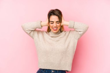 Orta yaşlı bir kadın, izole edilmiş arka planda kulakları elleriyle kapatıyor ve yüksek sesli sesler duymamaya çalışıyor..