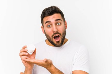 Kafkasyalı genç bir adam nemlendirici tutuyor. Palmiye üzerinde fotokopi alanı tutmaktan etkilenmiş..