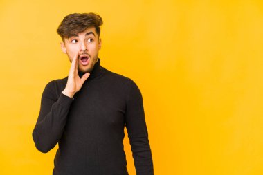 Sarı arka planda izole edilmiş genç bir Arap gizli bir sıcak fren haberi veriyor ve yana bakıyor.