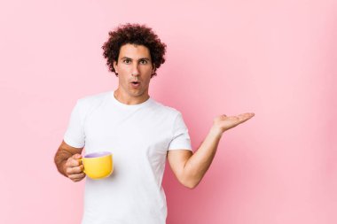 Elinde çay fincanı tutan beyaz, kıvırcık, genç bir adam....