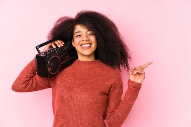 Elinde kaset tutan genç bir afro kadın gülümseyen ve işaret eden boş bir alanda bir şey gösteriyor..