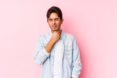 Pembe arka planda poz veren beyaz bir genç, virüs veya enfeksiyon yüzünden boğazında ağrı hissediyor..