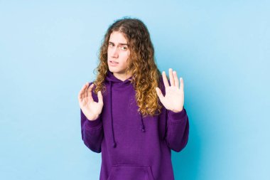 Uzun saçlı adam yalnız poz veriyor. İğrenme belirtisi gösteren birini reddediyor..