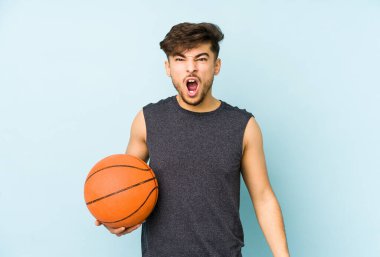 Young arabian man playing basket isolated screaming very angry and aggressive.