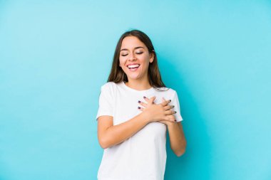 Kafkasyalı genç bir kadın yalnız gülüyor, ellerini yüreğine koyuyor, mutluluk kavramını koruyor..