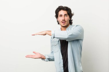 Beyaz arka planda genç ve yakışıklı bir adam elleri arasında bir kopya alanı tutarken şok ve hayrete düştü..