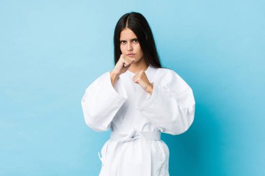 Mavi arka planda karate yapan beyaz bir kadın.