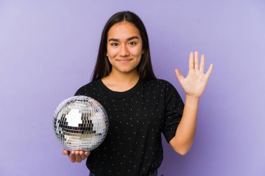 Genç Asyalı bir kadın bir balo partisi düzenliyor. Beş numarayı parmaklarıyla gülümsüyor..