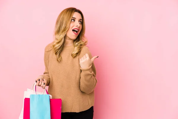 Ung Blond Kvinna Håller Shoppingpåsar Isolerade Punkter Med Tummen Fingret — Stockfoto